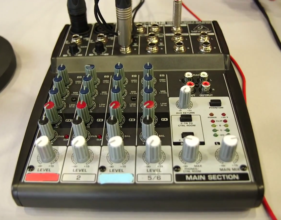 This is an image of a silver Behringer 802 Analog Mixer on a desk. It is a square mixer with various knobs and buttons visible.