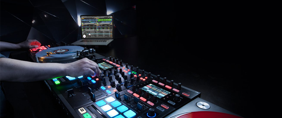 Against a plain black backdrop, a white hand mixes on a lit up Dj mixing desk. The lights on the desk are blue squares lit up.