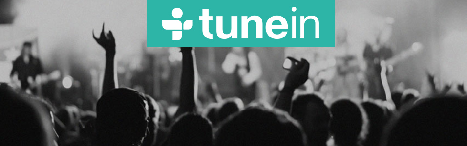 This is the TuneIn homepage. The top of the image is a black and white silhouetted club with people with their hands up.